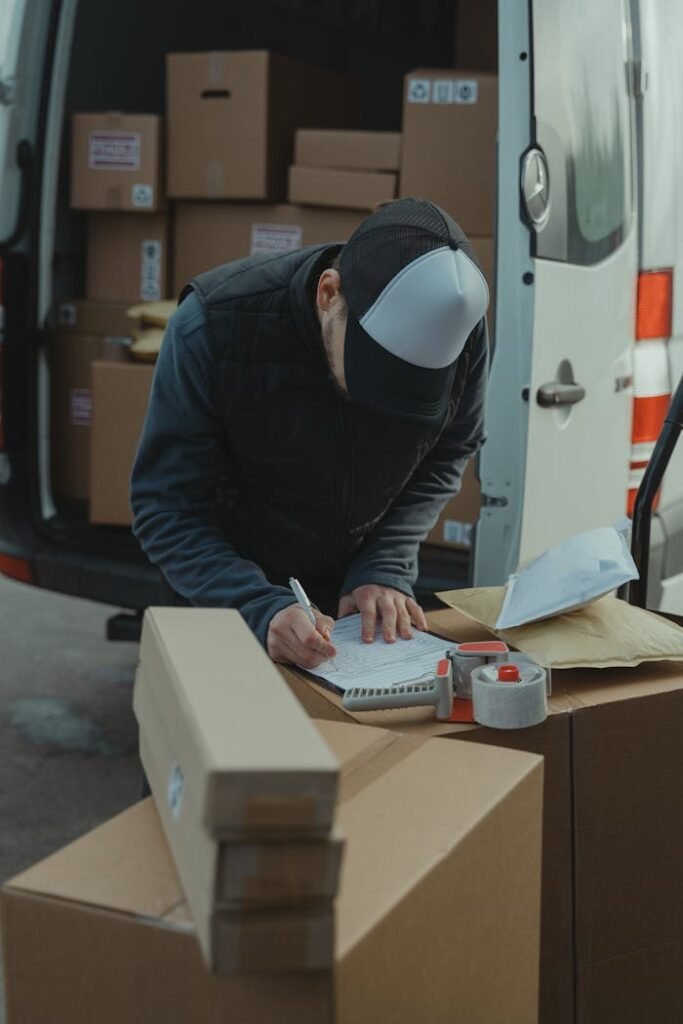pexels-photo-6169057 Courier organizing packages from a van, preparing for delivery in a logistics setting.
